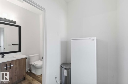 Bathroom vanity featuring a wood-finish cabinet, white countertop, and rectangular undermount sink - 17924 61 Street Nw, Edmonton, AB - Indoor Photo Showing Bathroom