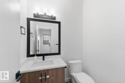 Modern bathroom vanity featuring a wood-finish cabinet with black hardware, a pristine white countertop, and an integrated rectangular sink - 