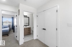 Hallway featuring plush carpet flooring, white walls, and contemporary black hardware on doors - 