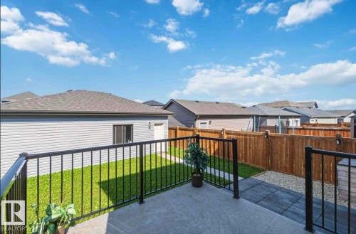 Concrete patio with black metal railings overlooking a landscaped backyard featuring a grass area, a gravel section with stepping stones, and wood fencing - 17924 61 Street Nw, Edmonton, AB - Outdoor With Deck Patio Veranda