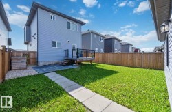 Expansive rear yard featuring a wooden privacy fence, a concrete paver walkway, and a gravel accent area - 