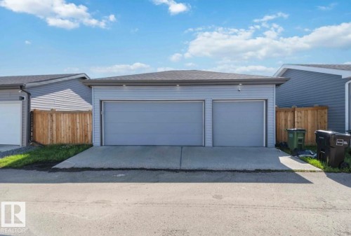 Detached garage featuring light gray siding, a dark gray shingled roof, and two gray panel garage doors - 17924 61 Street Nw, Edmonton, AB - Outdoor With Exterior