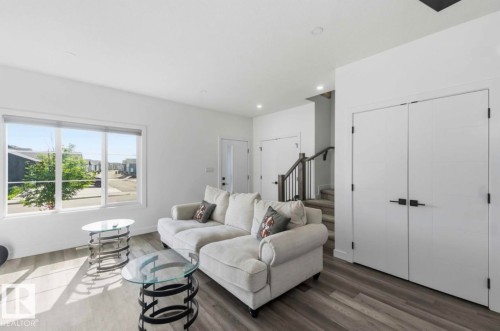 Spacious living area featuring large windows, wood-finish flooring, recessed lighting, and a neutral color palette - 17924 61 Street Nw, Edmonton, AB - Indoor Photo Showing Living Room