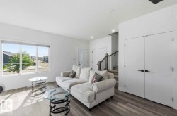 Spacious living area featuring large windows, wood-finish flooring, recessed lighting, and a neutral color palette - 