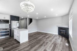Open-concept living space with wood-finish flooring, a contemporary fireplace with a dark stone surround, and recessed lighting - 