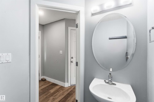 Pedestal sink with chrome faucet, large oval mirror, and three-light vanity bar - #64 120 Magrath Rd Nw, Edmonton, AB - Indoor Photo Showing Bathroom