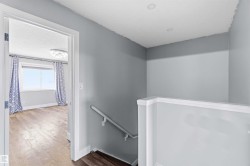 Upper landing featuring gray wall tones, recessed lighting, and a white balustrade - 