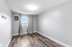 Light grey walls with white trim, wood-finish flooring, and a single window - 