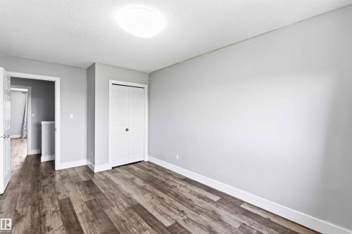 Room featuring wood-finish flooring, light grey painted walls, white baseboards, and a bi-fold closet - #64 120 Magrath Rd Nw, Edmonton, AB - Indoor Photo Showing Other Room