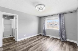 Light-filled room featuring wood-finish flooring, a contemporary ceiling light fixture, and a built-in shower enclosure with a glass door - 