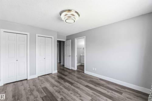 Spacious room featuring wood-finish flooring, two sets of bi-fold closet doors, and light gray wall paint - #64 120 Magrath Rd Nw, Edmonton, AB - Indoor