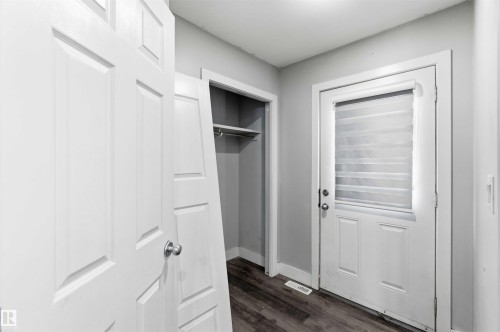Entryway featuring a white paneled door with round silver hardware, a closet with shelving and a hanging rod, a white exterior door with an inset privacy blind, and wood-finish flooring - #64 120 Magrath Rd Nw, Edmonton, AB - Indoor Photo Showing Other Room