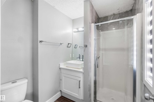 Modern bathroom featuring a glass-enclosed shower with tile surround, white floating vanity with vessel sink, and chrome fixtures - #64 120 Magrath Rd Nw, Edmonton, AB - Indoor Photo Showing Bathroom