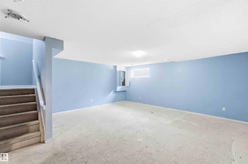 Spacious lower level room featuring light blue walls and carpeted flooring - #64 120 Magrath Rd Nw, Edmonton, AB - Indoor