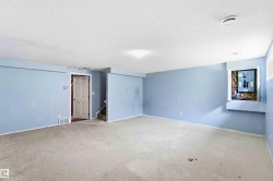 Expansive room featuring light blue walls and a neutral carpet - 