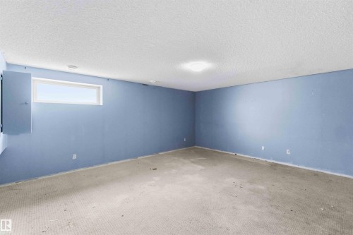 Spacious room featuring light blue walls, textured ceiling, a rectangular casement window, and recessed lighting - #64 120 Magrath Rd Nw, Edmonton, AB - Indoor