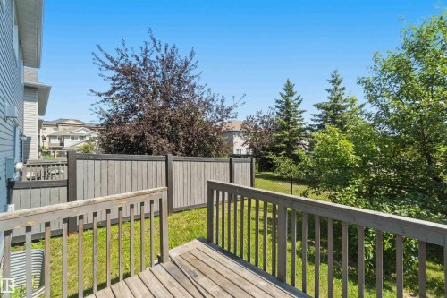 Wood deck with railings overlooking a fenced backyard with green lawn - #64 120 Magrath Rd Nw, Edmonton, AB - Outdoor