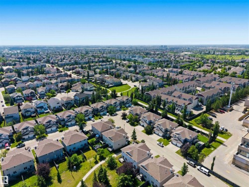 Aerial perspective showcasing a residential development with detached homes and multi-family buildings - #64 120 Magrath Rd Nw, Edmonton, AB - Outdoor With View