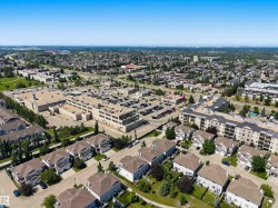 Expansive suburban landscape featuring residential homes with pitched roofs, a large commercial building with extensive parking, multi-story apartment buildings, and mature green spaces - 