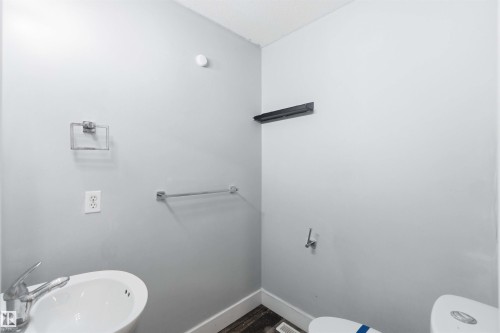 Pedestal sink with chrome faucet, complemented by a chrome towel ring and towel bar, set against light gray walls with dark baseboards - #64 120 Magrath Rd Nw, Edmonton, AB - Indoor Photo Showing Bathroom