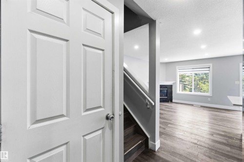 Four-panel interior door opening to a living area featuring wood-finish flooring, recessed lighting, and a window with horizontal blinds - #64 120 Magrath Rd Nw, Edmonton, AB - Indoor Photo Showing Other Room