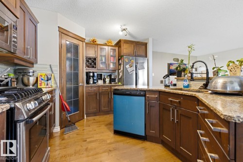Contemporary kitchen featuring wood-finish flooring, granite countertops, and stainless steel appliances - 3724 163 Avenue Nw, Edmonton, AB - Indoor Photo Showing Kitchen