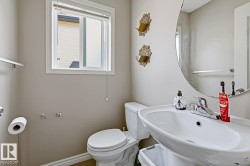 Bathroom featuring a single-pane window, wall-mounted oval mirror, and a white ceramic pedestal sink - 