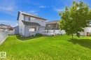 Rear exterior featuring blue siding, a multi-level deck with white railings, a large green lawn, and a mature tree - 3724 163 Avenue Nw, Edmonton, AB  - Outdoor 