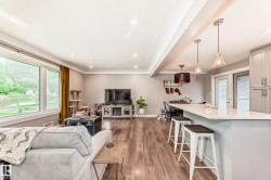 Open-concept living area with wood-finish flooring, recessed lighting, and large windows - 
