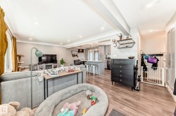 Open-concept living area with wood-finish flooring, recessed lighting, and crown molding - 