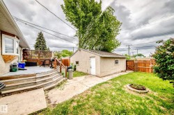Rear yard featuring a detached auxiliary building, wood privacy fencing, and a tiered wood deck with lattice railing - 
