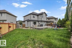 Expansive backyard featuring a large wood-finish deck, a substantial lawn area, and mature perimeter landscaping - 