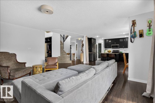 Open concept living area featuring dark wood-finish flooring, a white ceiling with a flush-mount light fixture, and light gray walls - 13 Baie Madelene, Beaumont, AB - Indoor Photo Showing Living Room