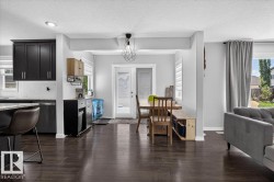 Open-concept living area featuring dark wood-finish flooring, light grey walls, and white trim - 