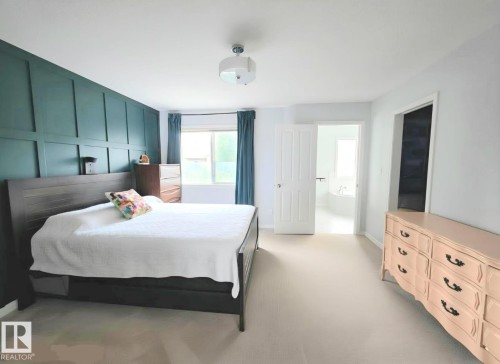 Bedroom featuring a dark teal accent wall with vertical and horizontal paneling - 13 Baie Madelene, Beaumont, AB - Indoor Photo Showing Bedroom