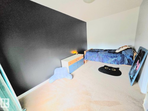Carpeted room with a textured dark accent wall and white painted walls - 13 Baie Madelene, Beaumont, AB - Indoor