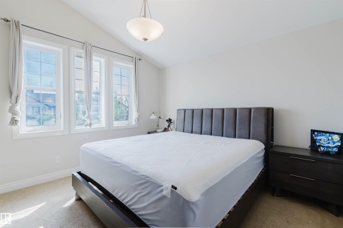 Bedroom featuring a vaulted ceiling, three large windows, and a flush-mount light fixture - 17348 6 Avenue Nw, Edmonton, AB - Indoor Photo Showing Bedroom