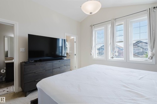 Room featuring three large windows, vaulted ceiling, neutral wall paint, and carpeted flooring - 17348 6 Avenue Nw, Edmonton, AB - Indoor Photo Showing Bedroom