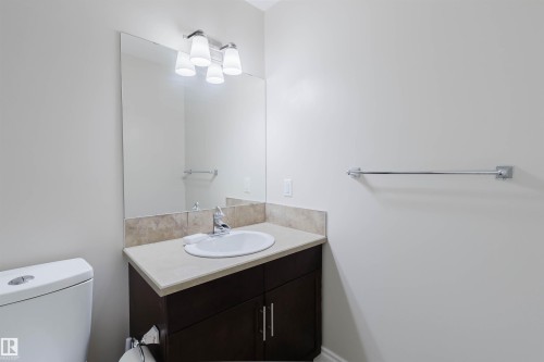 Bathroom featuring a vanity with a dark wood-finish cabinet, light countertop, and a white undermount sink - 17348 6 Avenue Nw, Edmonton, AB - Indoor Photo Showing Bathroom
