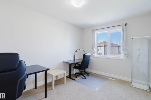 Spacious room featuring neutral paint, light-colored carpet, and a large window with white trim - 17348 6 Avenue Nw, Edmonton, AB - Indoor Photo Showing Office