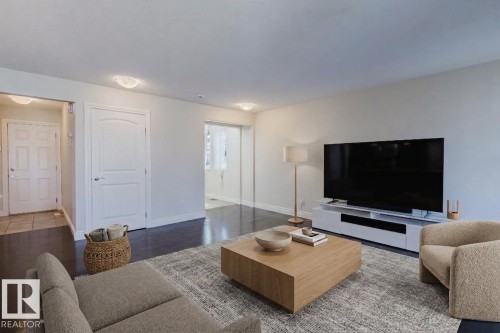 Interior space featuring dark wood-finish flooring, light-toned walls, white trim, and flush-mount lighting fixtures - 17348 6 Avenue Sw, Edmonton, AB - Indoor Photo Showing Living Room