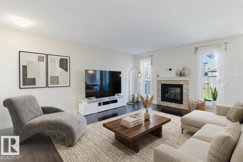 Living area featuring dark wood-finish flooring and a light-toned area rug - 17348 6 Avenue Sw, Edmonton, AB - Indoor Photo Showing Living Room With Fireplace
