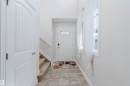 Entryway featuring ceramic tile flooring, a paneled front door with decorative glass insert, and a staircase with carpeted treads and a white handrail - 17348 6 Avenue Nw, Edmonton, AB  - Indoor Photo Showing Other Room 