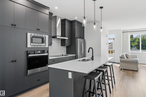 Kitchen featuring dark cabinetry, stainless steel appliances, and wood-finish flooring - 1439 Goodspeed Lane Nw, Edmonton, AB - Indoor Photo Showing Kitchen With Double Sink With Upgraded Kitchen