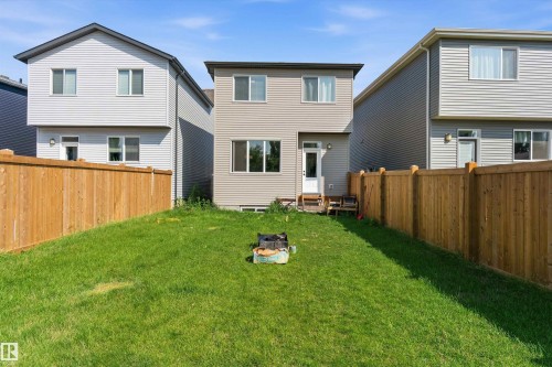 Spacious rear yard featuring a manicured lawn, full wood fencing, and a rear entrance with an elevated landing - 1439 Goodspeed Lane Nw, Edmonton, AB - Outdoor With Exterior