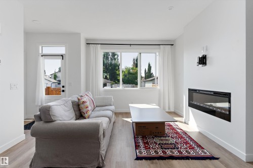 Living area featuring wood-finish flooring, an integrated electric fireplace, and a wall-mounted television bracket - 1439 Goodspeed Lane Nw, Edmonton, AB - Indoor Photo Showing Living Room With Fireplace