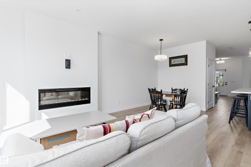 Contemporary living space featuring a linear electric fireplace with a white mantel, light wood-finish flooring, and recessed ceiling lighting - 1439 Goodspeed Lane Nw, Edmonton, AB - Indoor Photo Showing Living Room With Fireplace