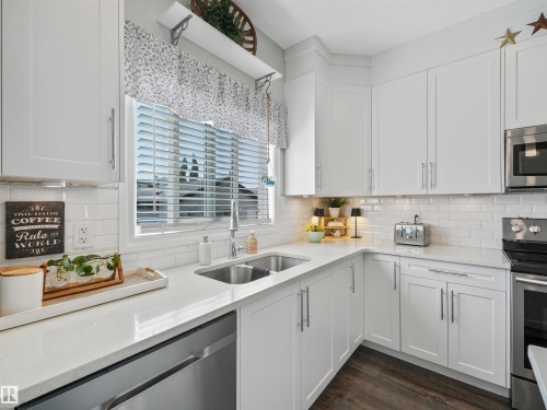 Modern kitchen featuring white shaker-style cabinetry, a white subway tile backsplash, and light-toned countertops - 283 Ameena Drive, Leduc, AB - Indoor Photo Showing Kitchen With Double Sink With Upgraded Kitchen