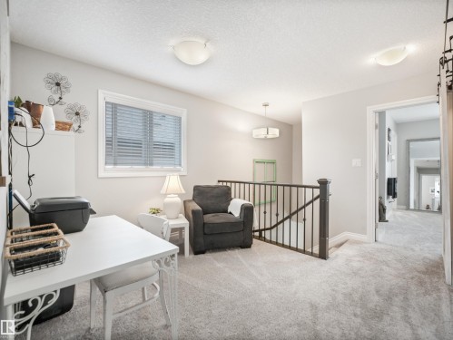 Carpeted upper-level landing featuring a large window with blinds, a dark wood newel post and balusters, and recessed lighting - 283 Ameena Drive, Leduc, AB - Indoor