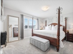 Carpeted bedroom featuring a large window with blinds, ceiling-mounted light fixture, and light gray wall paint - 